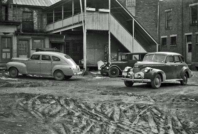 Automobiles parked on an unpaved lot in Worthington's business district, March 1940