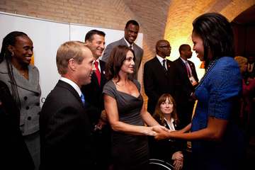 First Lady Michelle Obama greets gymnast Nadia Comaneci, her husband gymnast Bart Connor, left, Paralympic athlete Linda