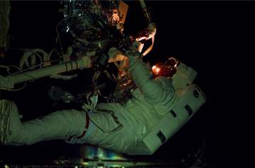 Gregory J. Harbaugh at work on Hubble Space Telescope (HST) on the remote manipulator system (RMS) at night during the s