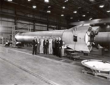 A group of officials standing before a Mercury-Redstone booster at the Marshall Space Flight Center (MSFC). Among those 