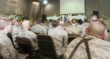 A host of U.S. and other NATO Training Mission-Afghanistan coalition servicemembers listen intently as former "Good Morn