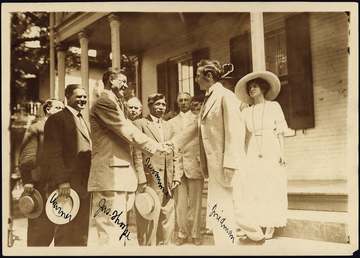Jim Thorpe shaking hands with Moses Friedman while Glenn "Pop" Warner, Lewis Tewanima, and a crowd look on.