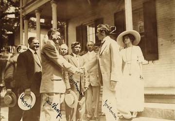 The photo shows Jim Thorpe in a business suit shaking hands with a group of admirers.