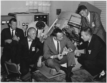 This is a photograph of John Glenn Jr. and others discussing the Mercury-Atlas 6 flight.