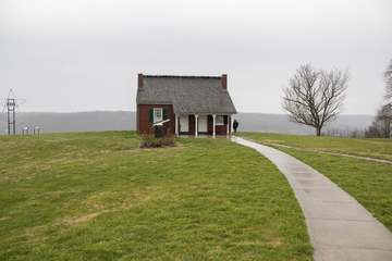 A red brick house with gray shingle roof and green yard with sidewalk leading to the house. The John Rankin house in Rip