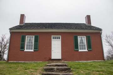 A red brick house with gray shingle roof and green yard with sidewalk leading down to the bottom. The John Rankin house 