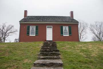 A red brick house with gray shingle roof and green yard with sidewalk leading down to the bottom. The John Rankin house 