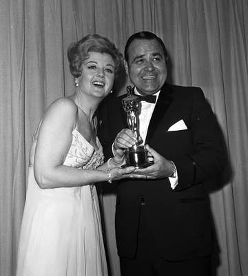 Comedian Jonathan Winters and actress Angela Lansbury posing with an Oscar at the 1965 Academy Awards. Winters had accep