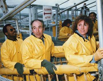 The STS-51L Challenger flight crew emergency egress training in the slide wire baskets. From left to right they are: Mis