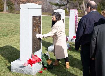 Amy Resnik, wife of Chuck Resnik, touches the Space Shuttle Challenger Memorial after a wreath laying ceremony as part o