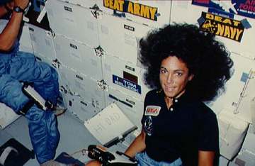 View of Mission Specialist Judith Resnik sitting on the floor of the middeck. Beside her on a notebook is a note which s