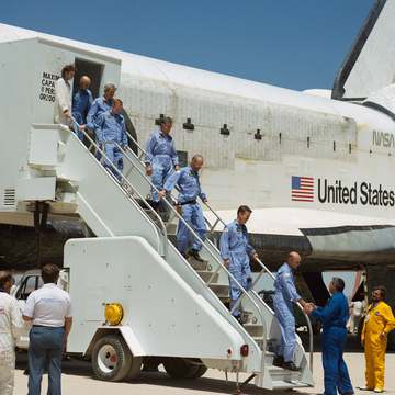 Mission Operations Director George W.S. Abbey, right, shakes hands with Astronaut C. Gordon Fullerton, as the seven-memb