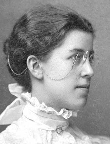 Katharine Wright mit Kneifer Brille und selten gut sichbarem Sicherheitskettchen mit Halt im Haar