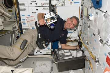 Astronaut Michael Good, STS-125 mission specialist, is busy unpacking equipment on Atlantis' middeck during his second d