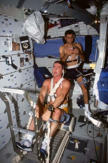STS-44 Pilot Terence T. Henricks (foreground) "rows" on the modified treadmill device used by crewmembers for biomedical