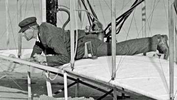 Wilbur Wright at the controls of the damaged Wright Flyer, on the ground after unsuccessful trial of December 14, 1903, 