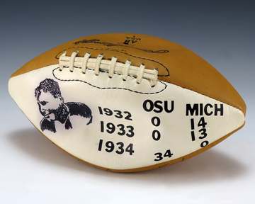 A football with an ink sketch of Gerald Ford and plastic stick-on letters state the scores of the Ohio State-Michigan ri